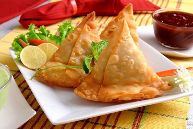 Crispy samosas are placed on a white plate with lemon slices and sauces in this dish wallpapers photo, 2K Desktop Wallpaper