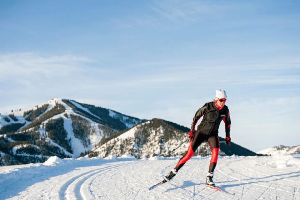 A skier wearing black and red gear skiing on snowy trails with mountain views, HD Desktop Wallpaper