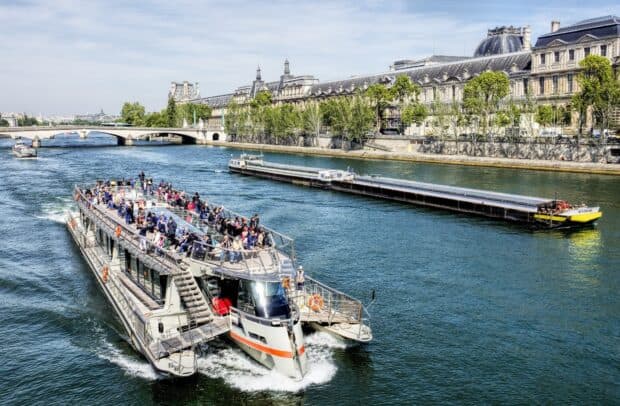 A crowded ferry is cruising on the river next to city buildings and a bridge, HD Desktop Wallpaper