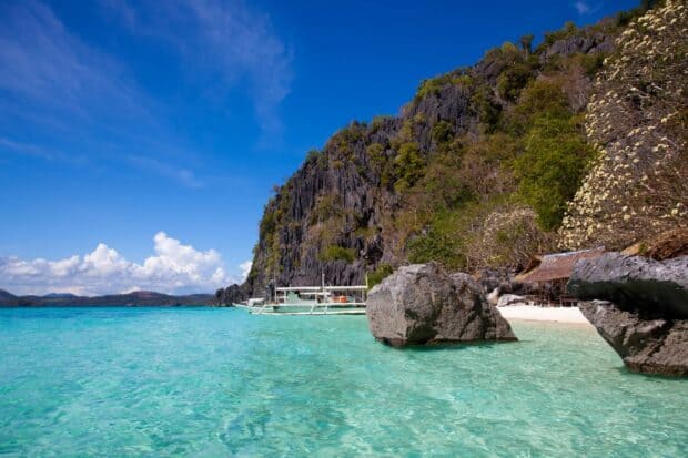 A traditional boat near limestone cliffs in Palawan shows the crystal clear turquoise water and bright sky, HD Desktop Wallpaper