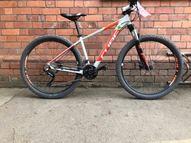 A Cube Bikes mountain bike stands against a brick wall outdoors, HD Desktop Wallpaper