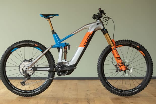 A Cube bike with blue and orange frame stands on wooden floor, HD Desktop Wallpaper