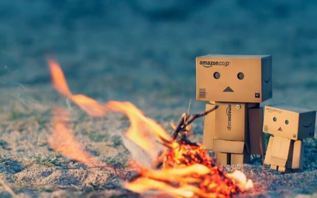 Two cardboard figures stand near a small campfire in a sandy area with an Amazon Wallpapers theme, HD Desktop Wallpaper