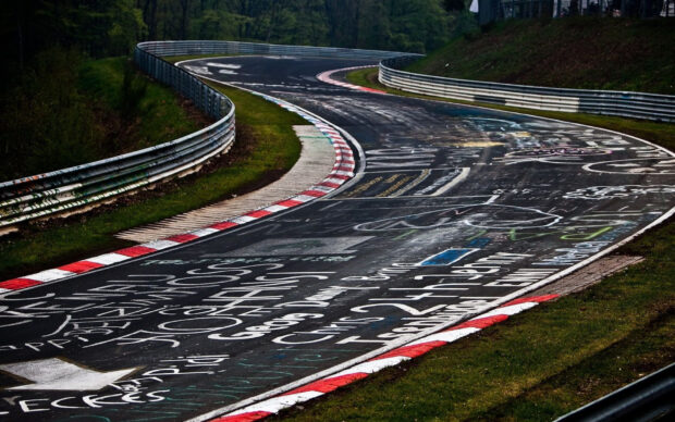 A curved race track with various graffiti and markings along the asphalt surface, HD Desktop Wallpaper