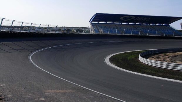 The race track features a sharp curved turn with empty grandstands in the background, HD Desktop Wallpaper