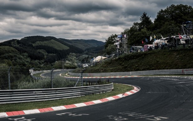 A winding race track surrounded by green hills and cloudy sky, HD Desktop Wallpaper