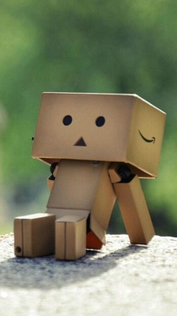 A small Amazon figure made of cardboard is sitting on a surface with a blurred green background, HD Phone Wallpaper