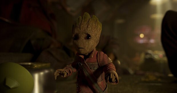 A young Groot character stands with a worried expression wearing a red outfit in a dimly lit scene, HD Desktop Wallpaper