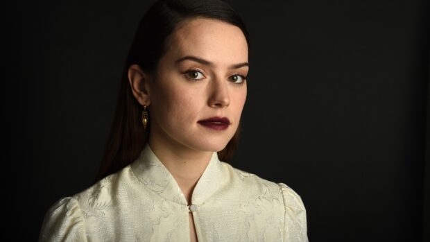 A portrait of Daisy Ridley wearing a cream textured top against a dark background, 4K Desktop Wallpaper