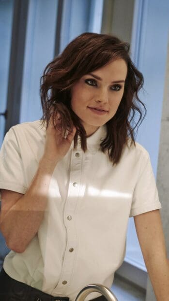 Daisy Ridley wears a white shirt while standing indoors near a window, 4K Phone Wallpaper