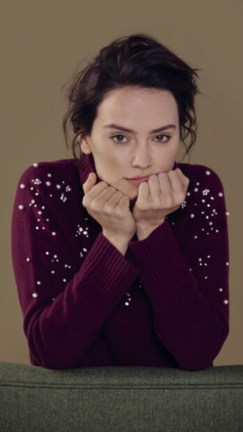 Daisy Ridley Wallpapers showing a woman in a maroon sweater with pearl details resting her chin on her hands, HD Phone Wallpaper