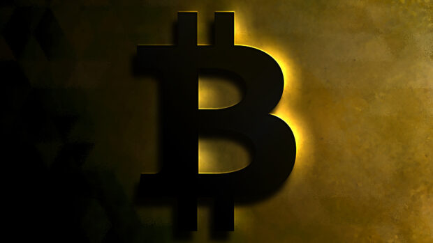 The Bitcoin symbol glows brightly against a dark textured gold background in this digital art, 4K Desktop Wallpaper