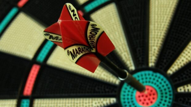 A darts wallpaper shows a sharp dart landing in the bullseye on the board, HD Desktop Wallpaper