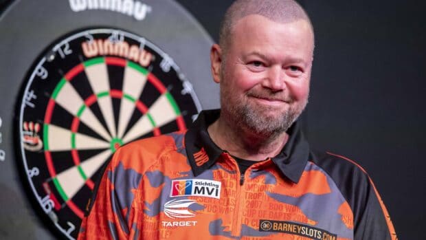 A darts player is standing close to a dartboard wearing an orange shirt, 4K Desktop Wallpaper