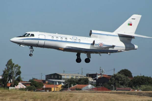 A Dassault Falcon 50 aircraft is flying low over a field near buildings, 2K Desktop Wallpaper