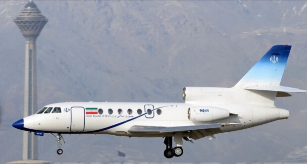 A Dassault Falcon 50 jet is captured flying near a mountain range with landing gear down, HD Desktop Wallpaper