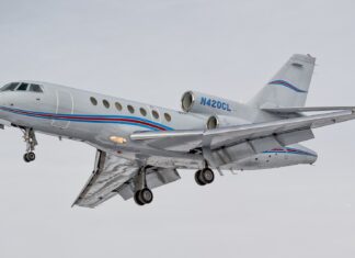 A Dassault Falcon 50 is captured flying with landing gear extended against a gray sky, HD Desktop Wallpaper