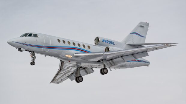 A Dassault Falcon 50 is captured flying with landing gear extended against a gray sky, HD Desktop Wallpaper