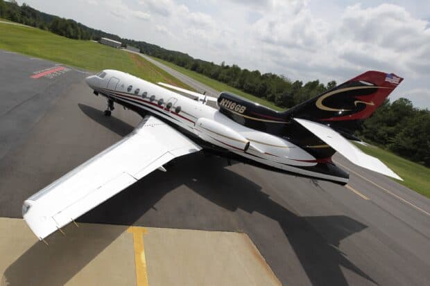 A Dassault Falcon 50 jet is parked on an airstrip near grassy fields under a cloudy sky, 2K Desktop Wallpaper