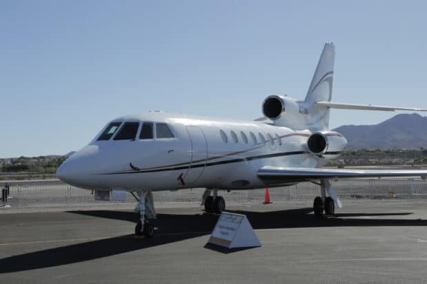 A Dassault Falcon 50 jet parked on the tarmac with mountains in the background, 2K Desktop Wallpaper