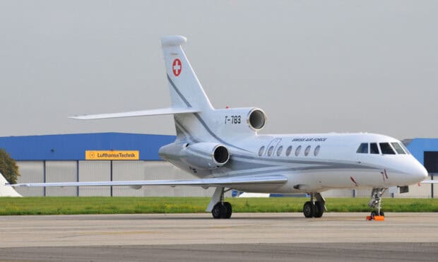 A Dassault Falcon 50 jet aircraft is parked on the runway near a hangar building, HD Desktop Wallpaper