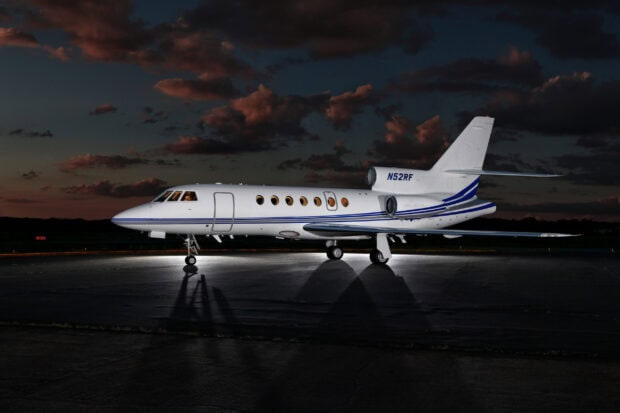 A Dassault Falcon 50 jet plane is parked on the runway under a dark sky with clouds, 2K Desktop Wallpaper