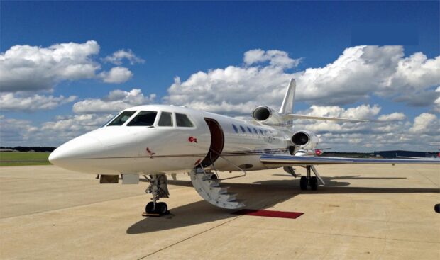 A white Dassault Falcon 50 jet with stairs extended stands on the runway under a cloudy blue sky, HD Desktop Wallpaper