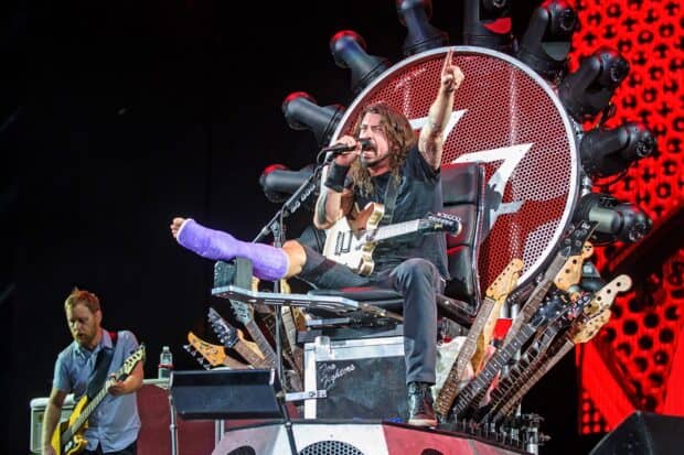 Dave Grohl is singing and playing guitar with a cast on his foot at a concert, HD Desktop Wallpaper