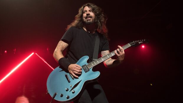 Dave Grohl plays guitar during a live concert under red lighting, HD Desktop Wallpaper