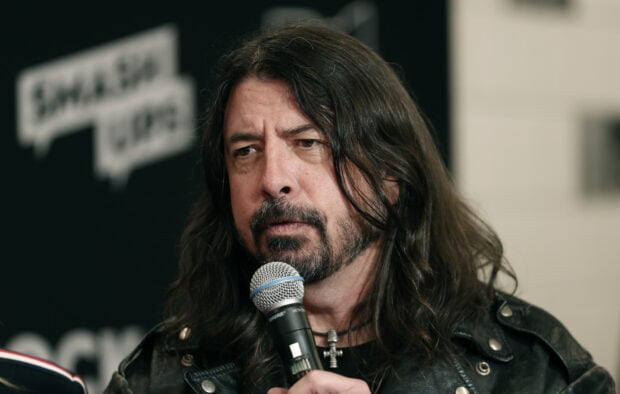 Dave Grohl is holding a microphone and speaking thoughtfully during an interview, HD Desktop Wallpaper