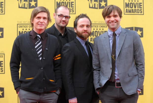 The Death Cab For Cutie band members posing at an awards event with yellow background, 2K Desktop Wallpaper