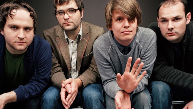 The members of Death Cab For Cutie are sitting together in a casual group pose, HD Desktop Wallpaper