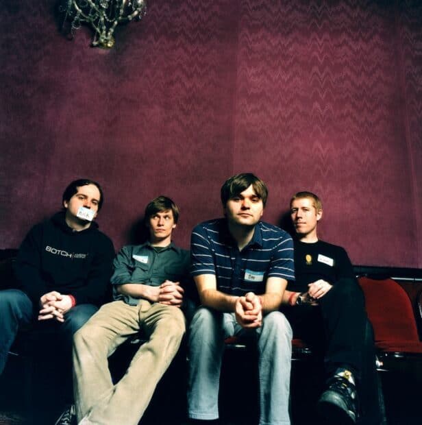 A photo of the band Death Cab For Cutie sitting in front of a textured maroon wall, HD Desktop Wallpaper