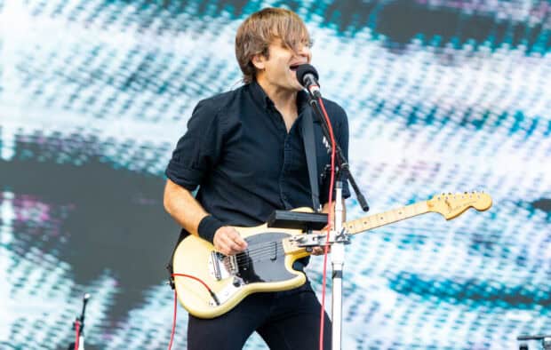 A musician from Death Cab For Cutie passionately sings and plays guitar on stage, HD Desktop Wallpaper