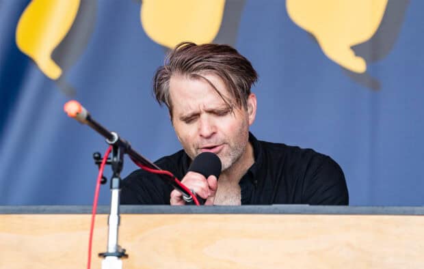 The lead singer of Death Cab For Cutie is singing into a microphone during a live performance, HD Desktop Wallpaper