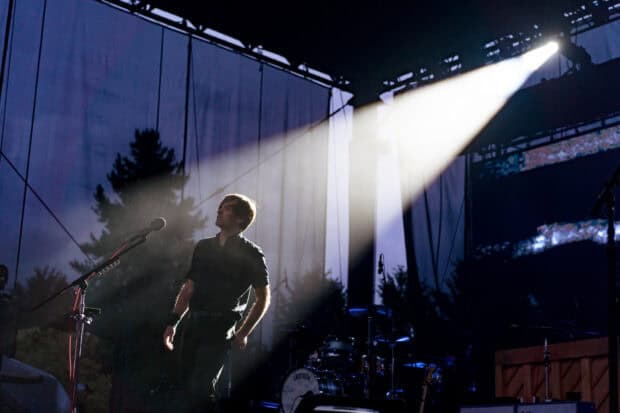 A band member of Death Cab For Cutie performs on stage under a spotlight, HD Desktop Wallpaper