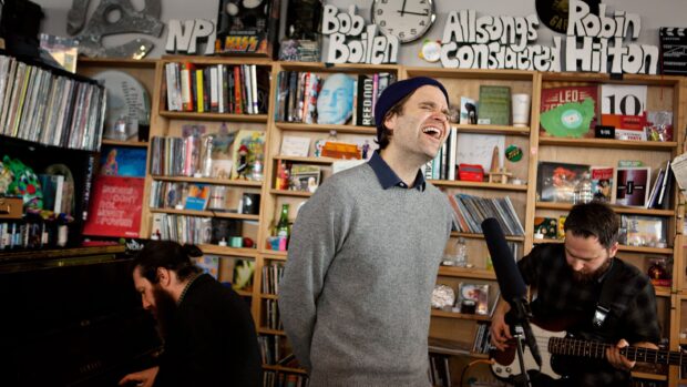 A man is singing passionately during the Death Cab For Cutie performance in a small room filled with records, 2K Desktop Wallpaper