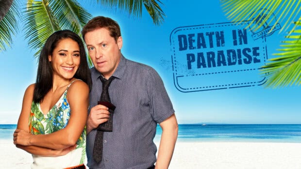 The main cast of Death In Paradise TV series stand smiling on a sunny beach under palm trees, 4K Desktop Wallpaper