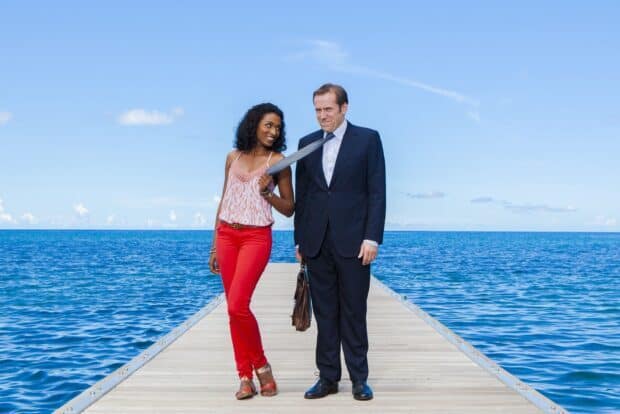Two main characters from Death In Paradise stand on a pier by the sea with a clear sky, HD Desktop Wallpaper