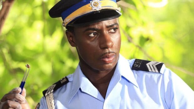A close up of an officer holding an investigative tool in Death In Paradise tv series wallpapers, HD Desktop Wallpaper