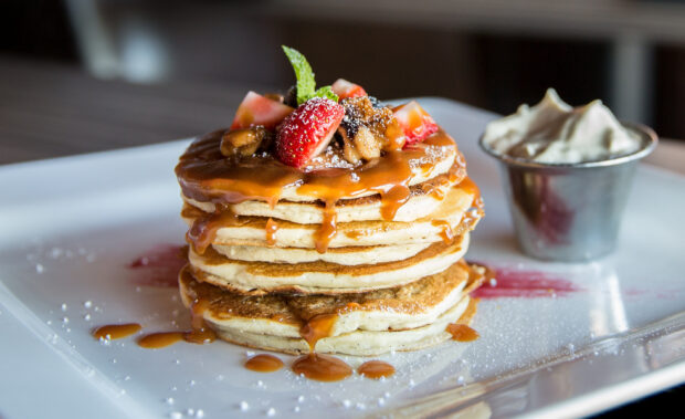 Delicious stack of pancakes with caramel sauce topped with strawberries and nuts, 2K Desktop Wallpaper