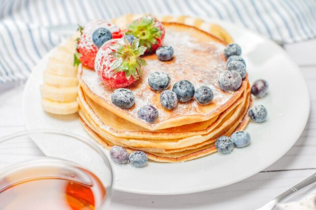 A stack of pancakes topped with strawberries and blueberries on a white plate, 2K Desktop Wallpaper