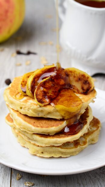 A stack of pancakes with honey drizzling over grilled banana slices on a white plate, 4K Mobile Wallpaper