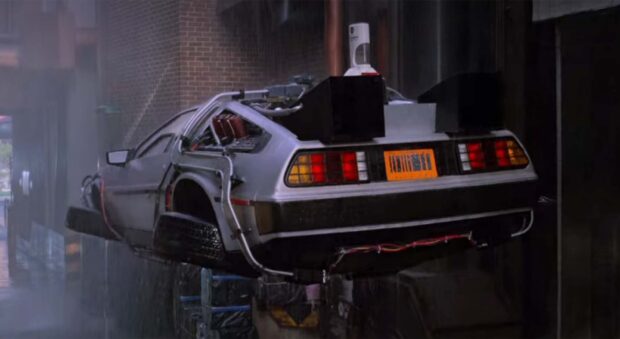 A Delorean Dmc 12 equipped with modifications is flying near a building, HD Desktop Wallpaper