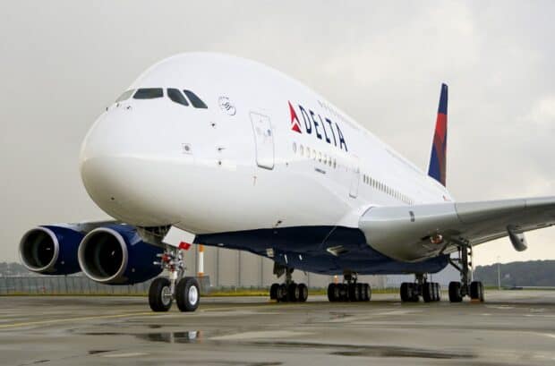 A Delta Air Lines Airbus A380 is parked on a wet runway under a cloudy sky, HD Desktop Wallpaper
