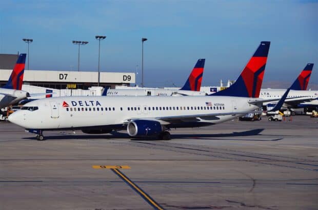 A Delta Air Lines airplane is parked at the airport gates with clear skies, 2K Desktop Wallpaper