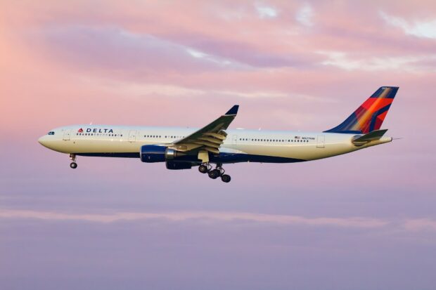 A Delta Air Lines airplane is flying with a colorful sunset sky in the background, HD Desktop Wallpaper