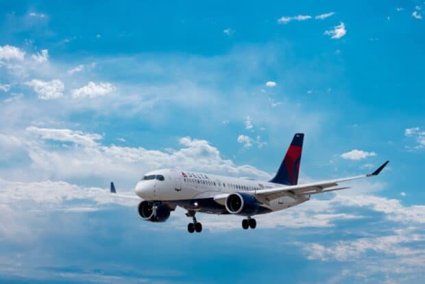 A Delta Air Lines plane is captured flying with clouds in the background, HD Desktop Wallpaper