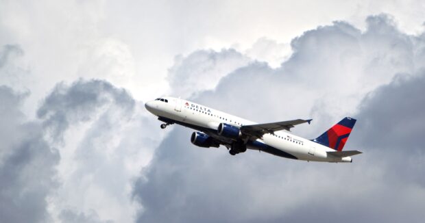 A Delta Air Lines aircraft is ascending through a cloudy sky in flight, 2K Desktop Wallpaper