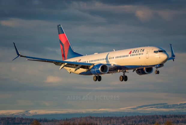 A Delta Air Lines airplane is flying over a snowy landscape during sunset, HD Desktop Wallpaper